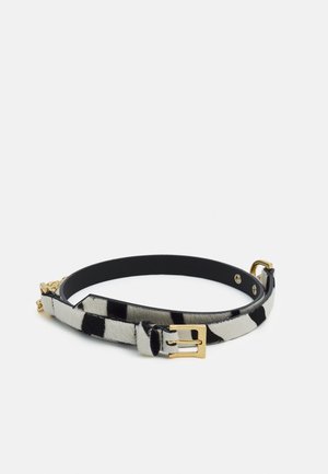 Zwart-wit gevlekte riem met een gouden rechthoekige gesp, lus en verstelbare gaten, liggend op een witte achtergrond.