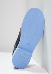 Sneaker blu scuro con superficie testurizzata, dotato di una suola in gomma blu chiaro con motivi scanalati per la trazione. Dettagli di cucitura lungo le cuciture.