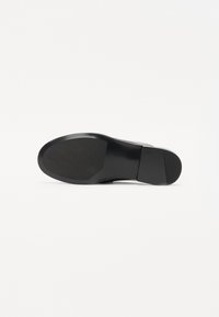 Suola di scarpa piatta nera con texture in gomma liscia, caratterizzata da una forma arrotondata e un design con minimo battistrada. Estetica pulita e semplice.