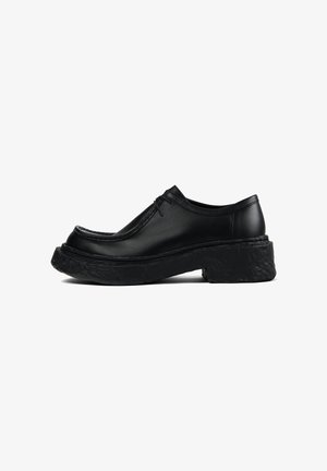 Schwarze Lederschuhe mit einem geschwungenen Design, strukturiertem schwarzen Plateausohle und Steppnähten entlang des Obermaterials. Merkmale sind eine abgerundete Zehenpartie und ein niedriger Schnitt.