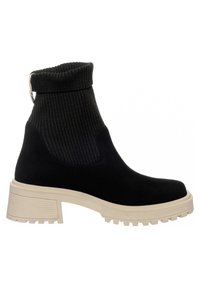 Czarny botek za kostkę z prążkowanym dzianinowym mankietem, zamszową cholewką, beżową masywną podeszwą i teksturowaną podeszwą zewnętrzną zapewniającą przyczepność. Z tyłu ozdobny hak.