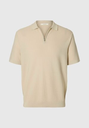 Polo beige à manches courtes avec un motif finement texturé et une courte fermeture éclair au col.