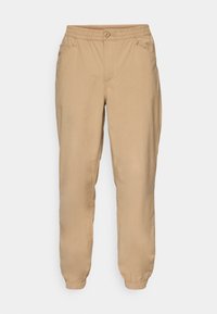 Beige elastic waist jogger pants with button closure, side pockets, and elastic cuffs.