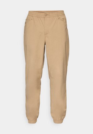 Beige elastic waist jogger pants with button closure, side pockets, and elastic cuffs.