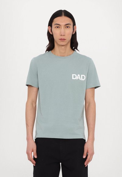 Světle modré bavlněné tričko s krátkým rukávem, kulatým výstřihem a bílým potiskem "DAD" na levé hrudi. Hladká textura, pohodlný střih.