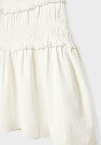 Weißes Baumwollkleid mit gerafftem Oberteil, eingeholten Rüschen und floralen Stickmustern auf dem Rock. Weicher Stoff und schwingende Form.