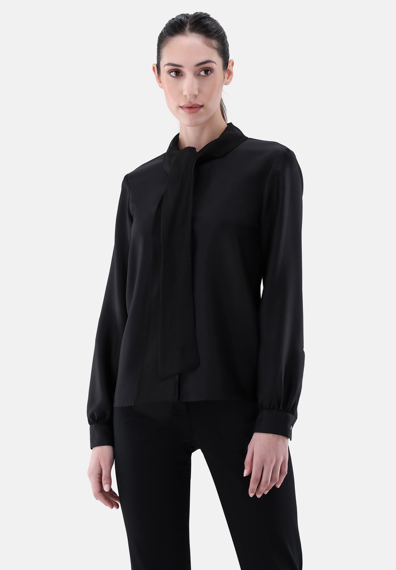 Black blouse with a tied neck detail, long sleeves, and buttoned cuffs. Smooth fabric with a slightly sheer quality, fitted silhouette.