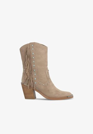 Beżowe zamszowe botki za kostkę z frędzlami, metalowymi ćwiekami i kwadratowym noskiem. Podeszwa na grubym obcasie z drewnopodobnym wykończeniem.