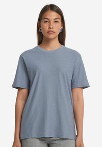 Ljusblå t-shirt med kort ärm, tillverkad av mjukt tyg, med rund halsringning och en avslappnad passform med subtil textur.