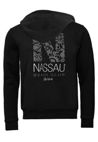 Mustapaita, jossa on suuri koristeellinen "N"-kirjain kukkakuviolla, ja valkoiset tekstit "NASSAU BEACH CLUB Ibiza" alla.