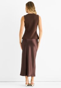 Brown sleeveless top with a textured knit and flowy satin brown skirt, featuring a slight A-line fit and minimalist design.