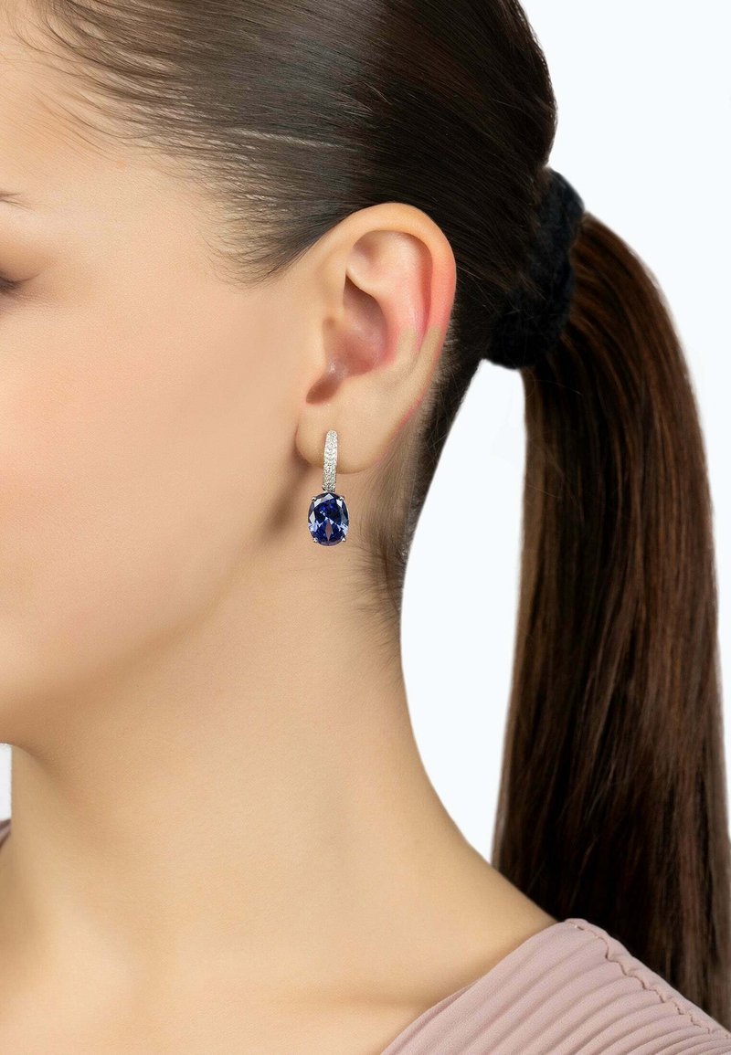 Sapphire drop earrings with a silver-tone textured hoop. The sapphire is oval-shaped and prominently displayed below the hoop.