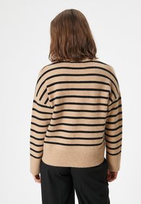 Maglione a righe in beige con strisce nere, caratterizzato da una vestibilità morbida e orli e polsini a coste, realizzato in un tessuto di maglia morbido.