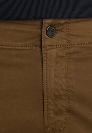 Pantalones de algodón marrones con una textura suave, que cuentan con un botón de metal y costura cerca de la cintura, con una cinturilla de canalé azul marino arriba.