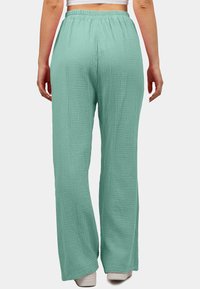 Mintgroene, wijde broek gemaakt van textiel met een elastische tailleband, met een losse pasvorm en een lengte tot op de vloer.