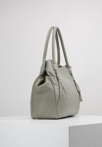 Szara skórzana torebka z dwoma długimi uchwytami, zaokrąglonym kształtem i subtelnymi zdobieniami ściegów. Zawiera dwa zamki błyskawiczne dla dodatkowej przestrzeni do przechowywania.