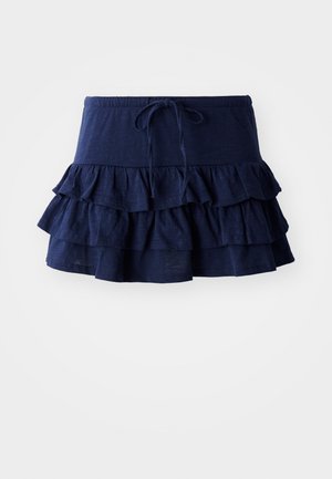 Jupe mini bleu marine à volants avec une ceinture à cordon de serrage. Comprend trois couches de fronces, fabriquée en tissu léger et doux.