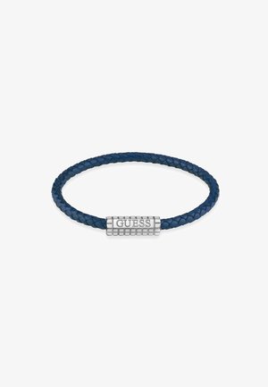 Sininen nahkaranneketju, jossa on hopeinen klipsi kaiverrettuna sanalla "GUESS", sileä pinta ja pyöreä muoto.