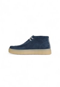 Bottines en suede bleu marine avec une surface texturée, des lacets gris et une semelle en caoutchouc beige dotée de rainures pour une meilleure adhérence.