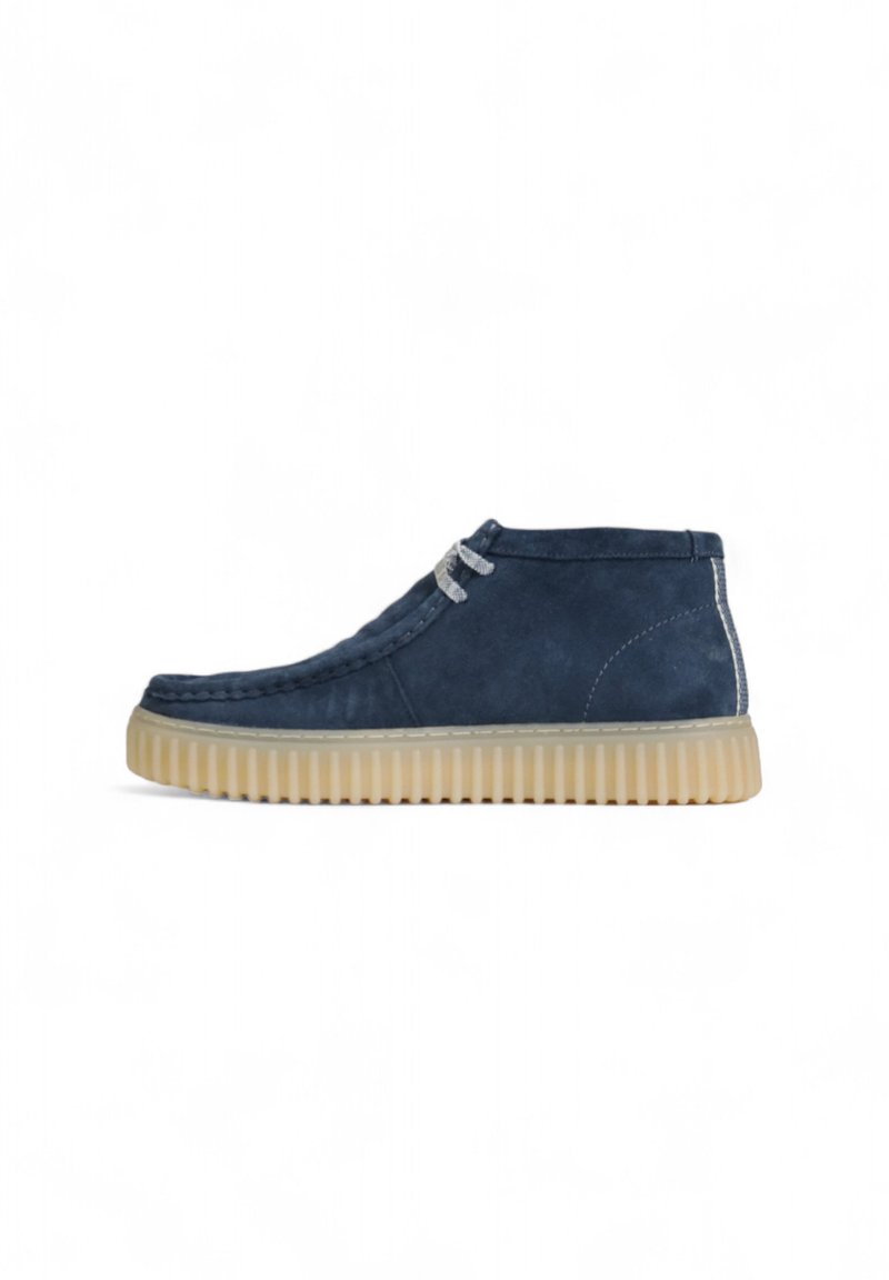 Bottines en suede bleu marine avec une surface texturée, des lacets gris et une semelle en caoutchouc beige dotée de rainures pour une meilleure adhérence.