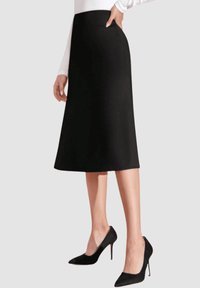 Falda negra en corte A, hecha de tela suave, que llega a la mitad de la pantorrilla, combinada con zapatos de tacón alto negros. Diseño sencillo sin patrones visibles.