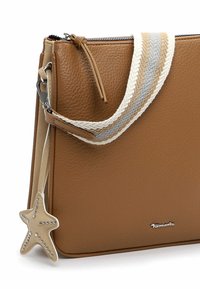 Tan leren crossbodytas met een gestructureerd oppervlak, gestreepte stoffen schouderriem, ritssluiting en een stervormige bedel met studs.