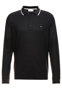 Svart långärmad polo tröja med vit krage, med en treknapps knappslå och liten logotyp på bröstet. Tillverkad av bomull.