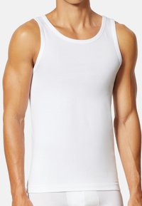 Weißes Baumwoll-Tanktop mit rundem Halsausschnitt und weiten Armausschnitten. Geschmeidige Textur und figurbetontes Design, geeignet zum Übereinandertragen oder für den Freizeitlook.