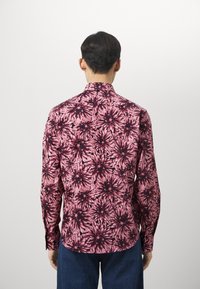 Langarmhemd mit einem pinken und schwarzen Blumenmuster, aus leichtem Stoff mit klassischem Kragen und Knopfmanschetten.