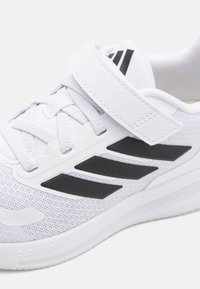 Baskets blanches avec tige en mesh, accents noirs et strap ajustable. Dispose de la technologie Cloudfoam pour l'amorti et le soutien.