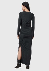 Musta pitkähiha dressi, jossa on ryppytys ja sivureikä. Valmistettu pehmeästä kankaasta, siinä on istuva siluetti ja elegantti, sulava muotoilu.
