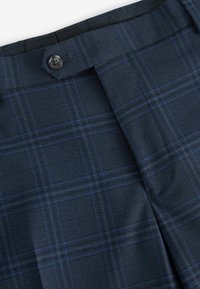 Navy plaid trousers with a blue check pattern, made from textured fabric, featuring a button closure and neatly folded front.