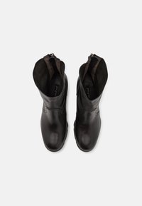 Paire de bottines en cuir noir avec bouts arrondis et fermetures éclair intérieures, vues de dessus sur un fond uni.
