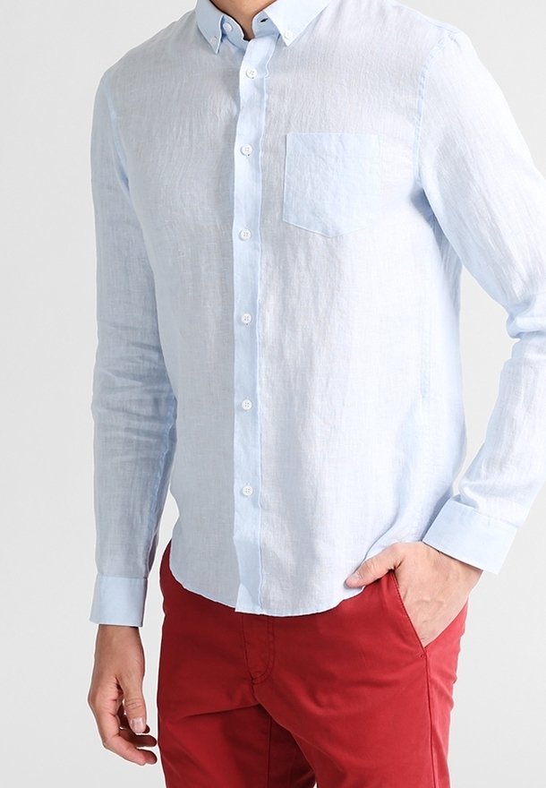 Ljusblå linneskjorta med knäppt krage, enda bröstficka och långa ärmar, kombinerad med röda byxor. Mjuk, texturerad tyg.