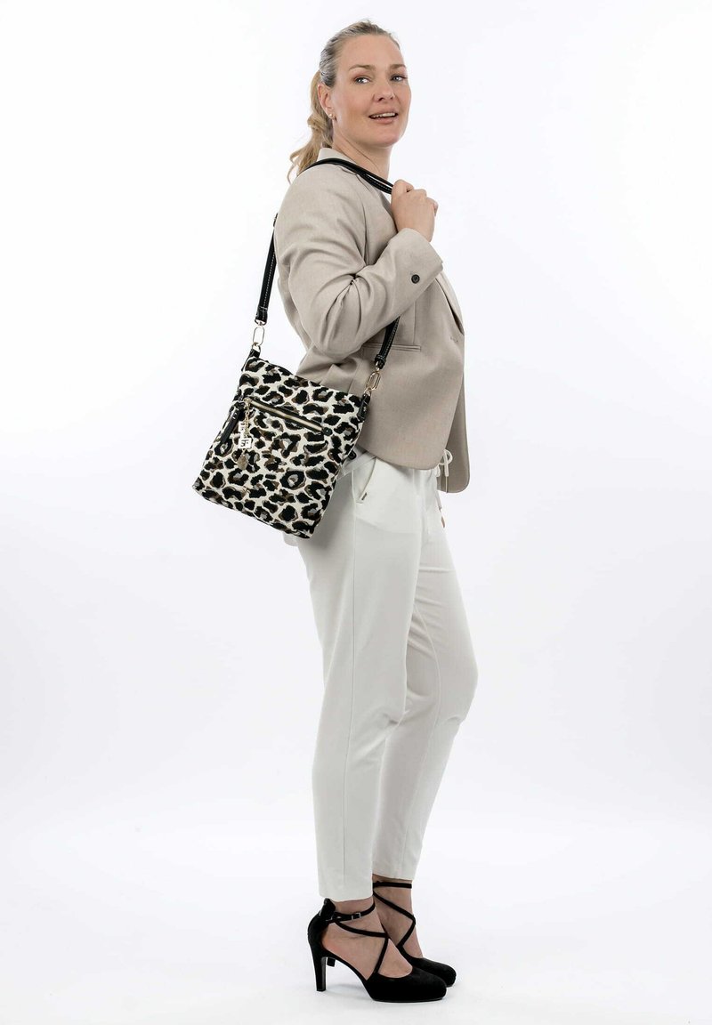 Leopard print handbag with black leather accents, a top zipper, and adjustable strap. Structured shape and textured fabric.