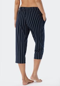 Marineblå randiga cropped byxor med elastisk midja och sidofickor. Tillverkade av mjukt tyg med vertikala vita ränder.