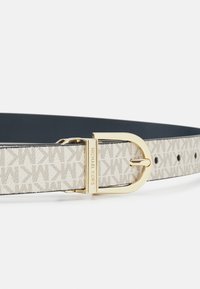 Ceinture en toile beige avec un motif répétitif du logo MK. Dotée d'une boucle en métal doré et d'un intérieur en cuir noir. Ajustable avec des trous.