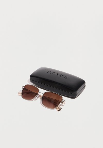 Ορθογώνια γυαλιά ηλίου με καφέ φακούς και χρυσό πλαίσιο δίπλα σε μαύρη θήκη με το λογότυπο Ralph Lauren σε λευκό φόντο.