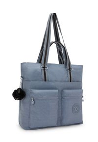 Sininen kangaskassi, jossa on kaksi etutaskua vetoketjulla, mustavalkoraidalliset olkahihnat ja mustasta karvasta valmistettu avaimenperä kiinnitettynä sivulle.