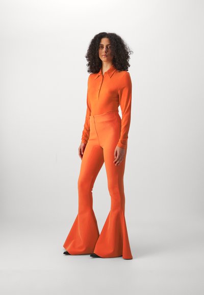 Orange ribbed knit top with a collared neckline and long sleeves, paired with matching flared trousers. Smooth texture, fitted silhouette.