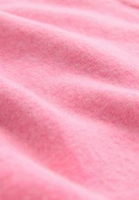 Tela de forro polar rosa suave con una textura lisa y un brillo sutil, que presenta ondas suaves y un tejido uniforme y consistente.