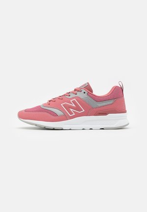 Chaussure de sport New Balance rose et grise avec semelle blanche, lacets latéraux et grand logo "N" sur le côté.