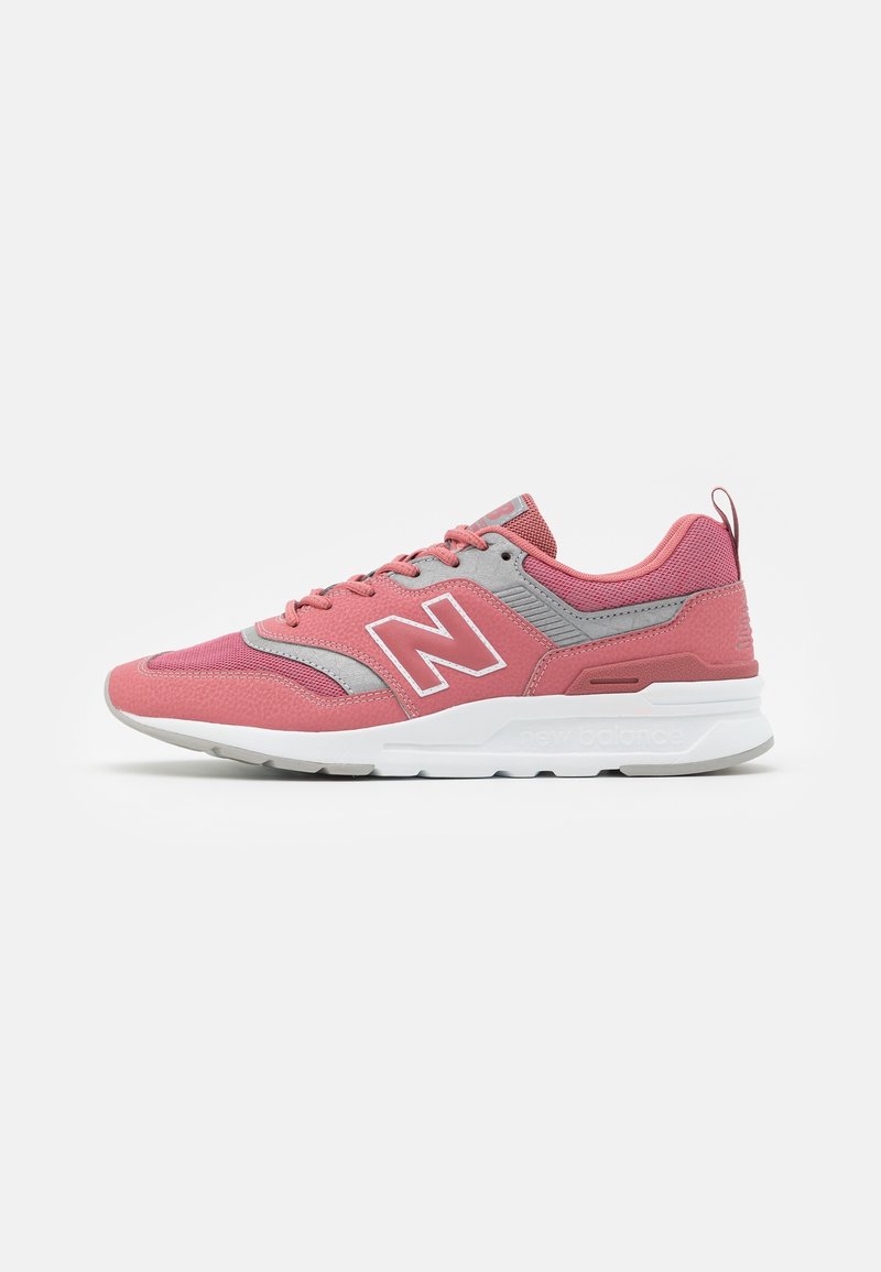 Chaussure de sport New Balance rose et grise avec semelle blanche, lacets latéraux et grand logo "N" sur le côté.