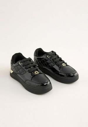 Czarne sneakersy z błyszczącej patentowanej skóry i akcentami w krokodylą fakturę, z pikowanym wzorem, czarnymi sznurowadłami i złotymi detalami.