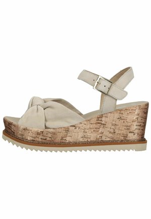 Beige suede wedge sandal with knotted front, cork-textured platform, and adjustable ankle strap. Features a serrated rubber sole for grip.