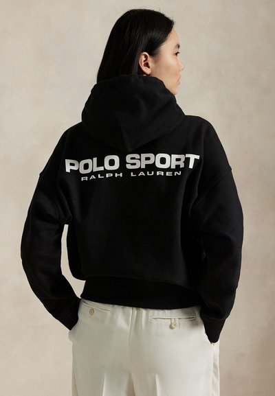 Juodas trumpintas džemperis su gobtuvu, pagamintas iš minkštos medžiagos, ant nugaros didelis baltas logotipas „POLO SPORT“ ir unikalus gobtuvo raištelių dizainas.