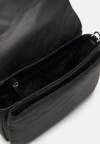 Borsa a mano in nylon nero con texture liscia, dotata di molteplici scomparti e una tasca con zip. Design minimalista, forma rettangolare.