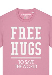 Roze katoenen t-shirt met vetgedrukte witte tekst: "FREE HUGS" boven "TO SAVE THE WORLD." Ronde halsontwerp, zachte textuur, casual pasvorm.
