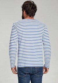 Langærmet skjorte med blå og hvide vandrette striber, lavet af blødt stof, med rund halsudskæring og afslappet pasform, båret med blå jeans.