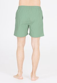 Gröna simshorts tillverkade av lättviktig tyg. Har elastisk midja, sidofickor och en avslappnad passform som når mitt på låret.